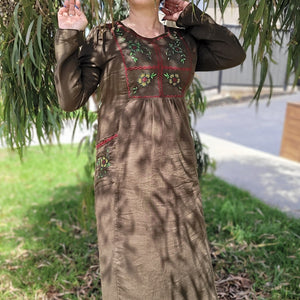 Honey-embroidered-maxi-dress-in-khaki-brown-featuring-embroidery-on-bust-and-front-pockets-front-view-under-tree