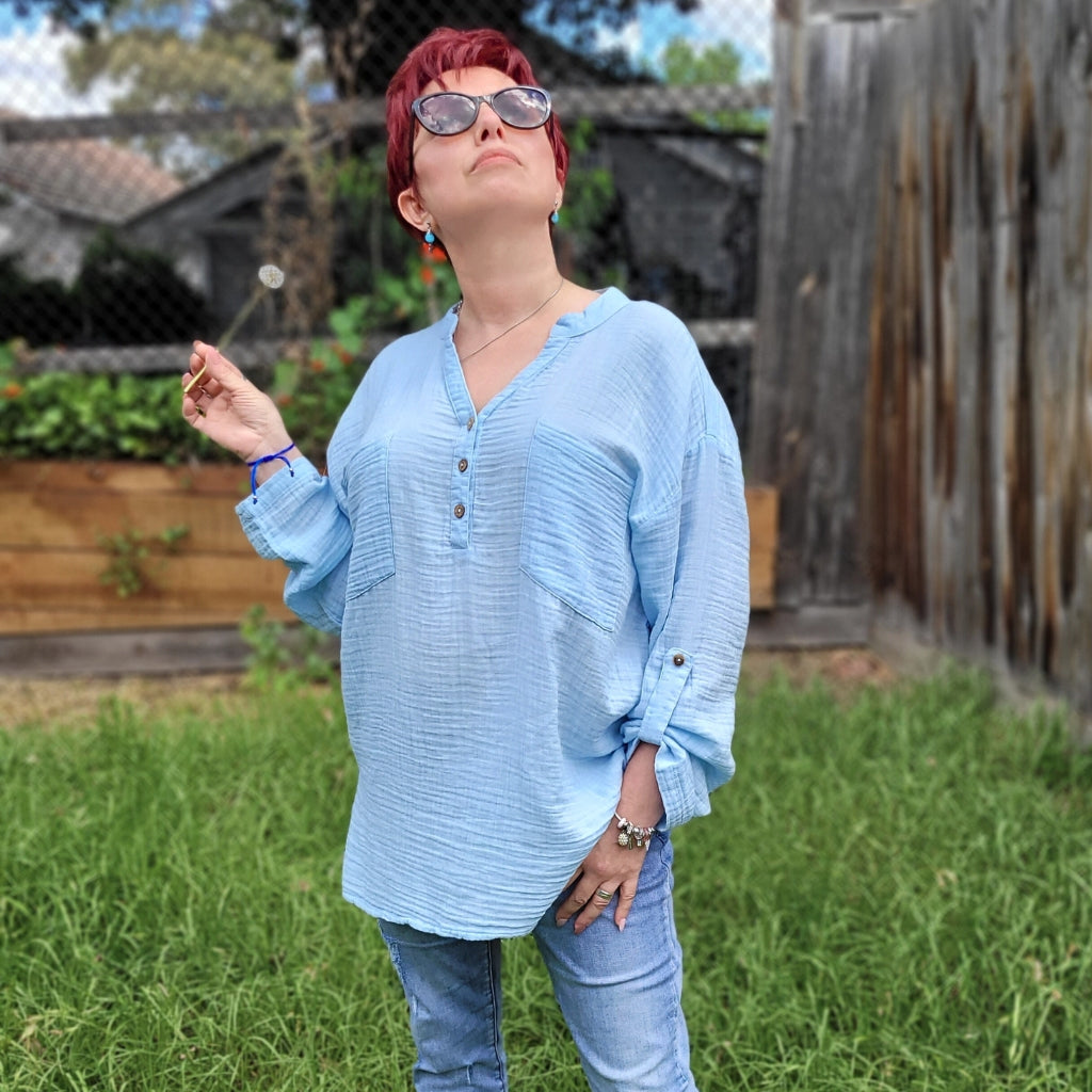 Ada-long-sleeve-Vneck-muslin-blouse-features-front-pockets-and-sleeve-tabs-in-ice-blue-worn-with-jeans-outdoor-image