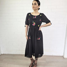 Load image into Gallery viewer, ashley-embroidered-midi-dress-with-embroidery-and-lace-detail-on-bodice-and-front-pockets-and-lace-on-hem-trim-in-black-indoor-image
