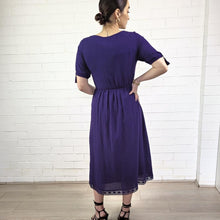 Load image into Gallery viewer, ashley-embroidered-midi-dress-with-embroidery-and-lace-detail-on-bodice-and-front-pockets-and-lace-on-hem-trim-in-purple-back-view
