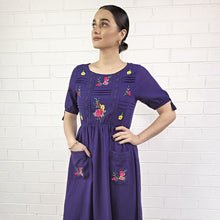 Load image into Gallery viewer, ashley-embroidered-midi-dress-with-embroidery-and-lace-detail-on-bodice-and-front-pockets-and-lace-on-hem-trim-in-purple-close-up-view
