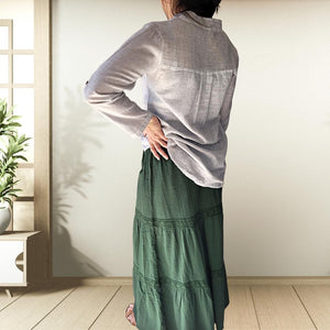 dahlia-tiered-maxi-skirt-with-lace-trim-in-green-worn-with-V-neck-blouse-in-stone-brown-sandals-back-view