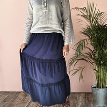 Load image into Gallery viewer, dahlia-tiered-maxi-skirt-with-lace-trim-in-navy-worn-with-V-neck-blouse-in-stone-and-brown-leather-sandals-front-view
