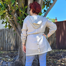 Load image into Gallery viewer, delta-hooded-tunic-with-button-tab-long-sleeves-drawstring-waist-and-front-pockets-in-light-grey-back-view-showing-buttoned-slit
