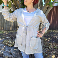 Load image into Gallery viewer, delta-hooded-tunic-with-button-tab-long-sleeves-drawstring-waist-and-front-pockets-in-light-grey-front-close-up-view
