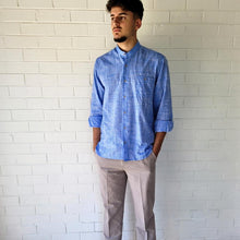 Load image into Gallery viewer, long-sleeve-shirt-with-band-collar-button-up-front-and-single-chest-pocket-in-speckled-blue-worn-with-chino-pants-in-light-grey-front-view
