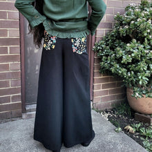 Load image into Gallery viewer, Luna high-waisted, wide leg, brushed cotton, women&#39;s pants in black, back view showing floral detail on back pockets, worn with green tunic
