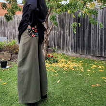 Load image into Gallery viewer, Luna high-waisted, wide leg, brushed cotton, women&#39;s pants in khaki, side view showing back pocket floral detail, worn with black tunic 
