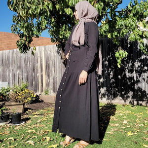 long-sleeve-button-through-cotton-maxi-dress-in-black-with-fabric-belt-shirt-collar-buttoned-cuffs-and-gathered-tier-in-skirt-from-the-hips-side-view