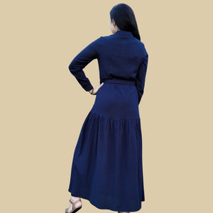 long-sleeve-button-through-cotton-maxi-dress-in-navy-with-fabric-belt-shirt-collar-buttoned-cuffs-and-gathered-tier-in-skirt-from-the-hips-back-view