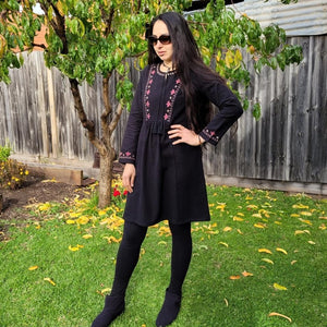 long-sleeve-brushed-cotton-tunic-dress-in-black-with-embroidery-detail-on-front-panel-and-sleeve-cuffs-and-round-string-tie-neck