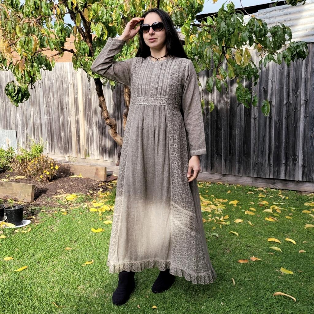 long-sleeve-cotton-maxi-dress-in-mocha-with-eyelet-embroidery-on-front-sides-pintuck-detail-on-chest-lace-frill-at-skirt-hem-and-string-tie-at-waist-back