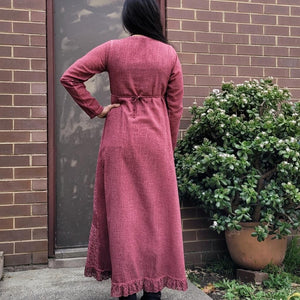 long-sleeve-cotton-maxi-dress-in-rose-with-eyelet-embroidery-on-front-sides-pintuck-detail-on-chest-lace-frill-at-skirt-hem-showing-string-tie-at-waist-back