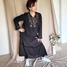 Load image into Gallery viewer, selena-long-sleeve-tunic-with-round-string-tie-neck-embroidery-on-chest-panel-and-lace-detail-and-ruffles-on-the-sleeve-ends-and-hemline-in-black-worn-with-maxi-skirt-front-view
