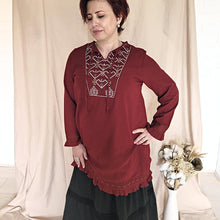 Load image into Gallery viewer, selena-long-sleeve-tunic-with-round-string-tie-neck-embroidery-on-chest-panel-and-lace-detail-and-ruffles-on-the-sleeve-ends-and-hemline-in-crimson-worn-with-maxi-skirt-front-view
