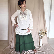 Load image into Gallery viewer, selena-long-sleeve-tunic-with-round-string-tie-neck-embroidery-on-chest-panel-and-lace-detail-and-ruffles-on-the-sleeve-ends-and-hemline-worn-with-belt-in-cream-front-view
