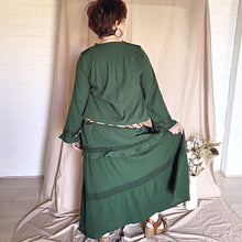 Load image into Gallery viewer, selena-long-sleeve-tunic-with-round-string-tie-neck-embroidery-on-chest-panel-and-lace-detail-and-ruffles-on-the-sleeve-ends-and-hemline-in-green-worn-with-belt-back-view
