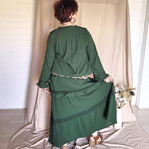 selena-long-sleeve-tunic-with-round-string-tie-neck-embroidery-on-chest-panel-and-lace-detail-and-ruffles-on-the-sleeve-ends-and-hemline-in-green-worn-with-belt-back-view