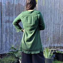 Load image into Gallery viewer, selena-long-sleeve-tunic-with-round-string-tie-neck-embroidery-on-chest-panel-and-lace-detail-and-ruffles-on-the-sleeve-ends-and-hemline-in-green-outdoor-back-view
