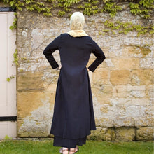 Load image into Gallery viewer, zahra-asymmetric-maxi-dress-with-layered-asymmetric-skirt-button-detail-on-front-in-black-back-view-in-front-of-wall
