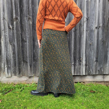 Load image into Gallery viewer, back-view-of-high-waisted-brushed-cotton-flannel-maxi-skirt-in-khaki-with-ditsy-floral-print-accent-pocket-on-front-right-in-solid-khaki-and-button-through-off-centre-front-slit
